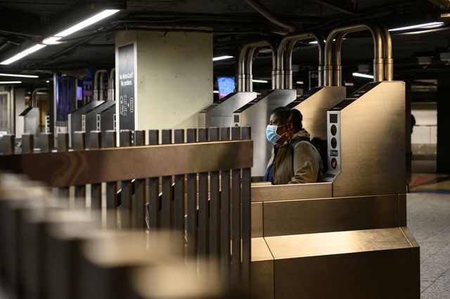 A person wearing a mask walks through a turnstile on April 30, 2020